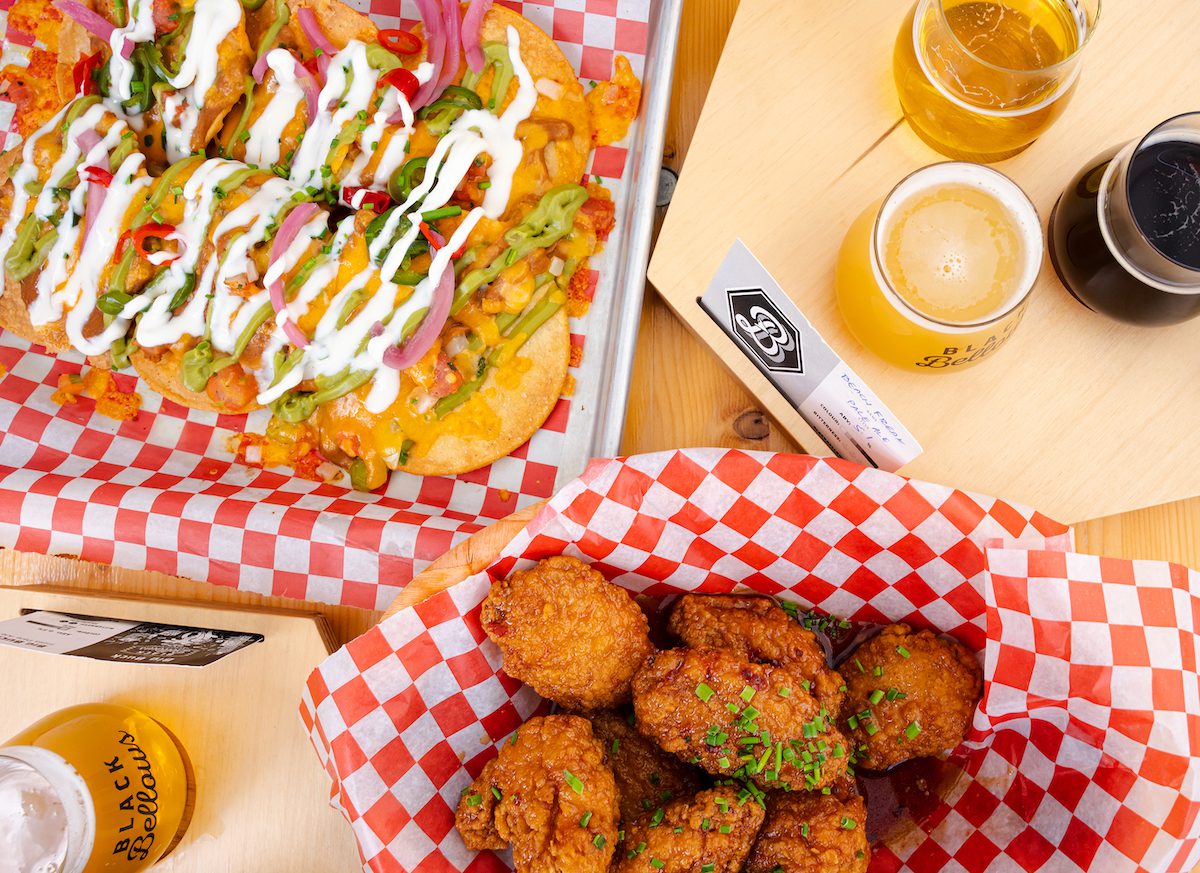 black bellows overhead shot of chicken wings, beer and tostadas