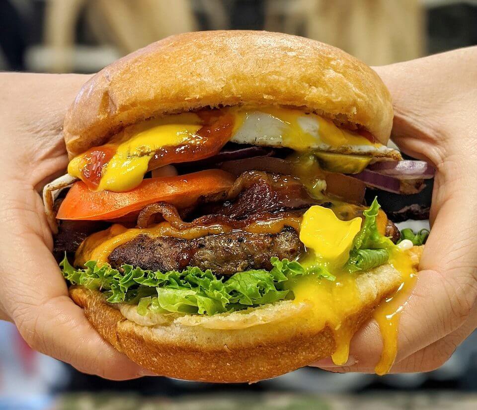 giant juicy burger being held by two hands