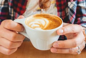 close up of hands holding a cappucino in a white mug at gibson and co.