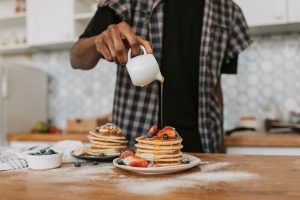 pouring maple syrup over pancakes