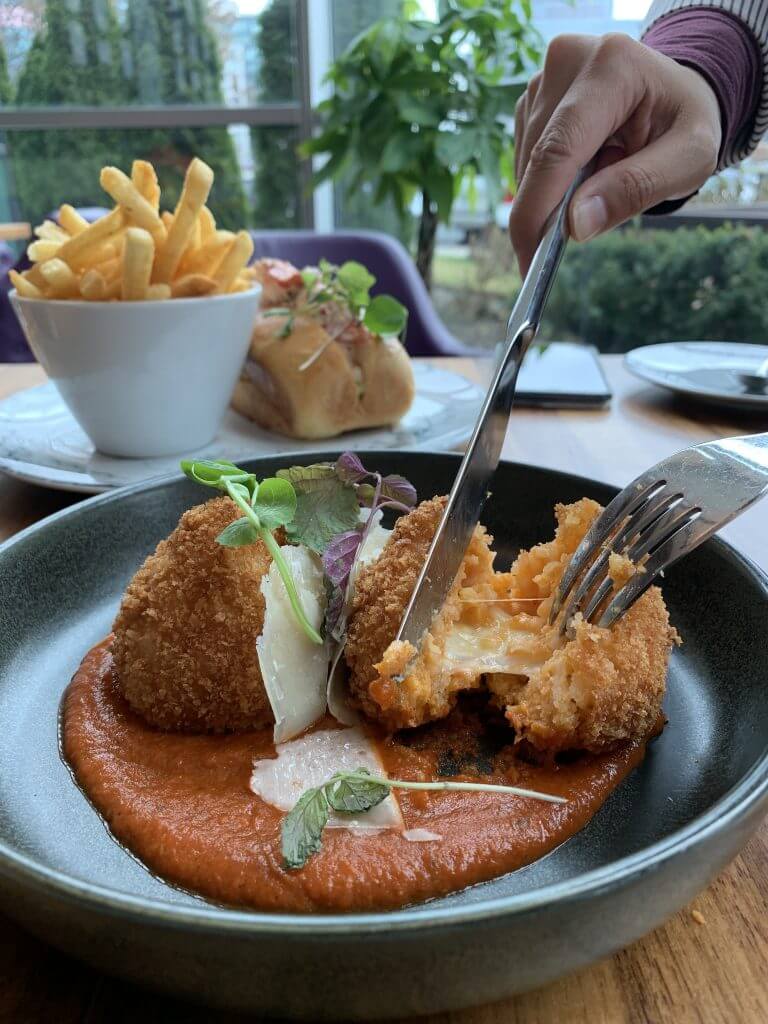 cutting into a dish that looks like arancini in markham