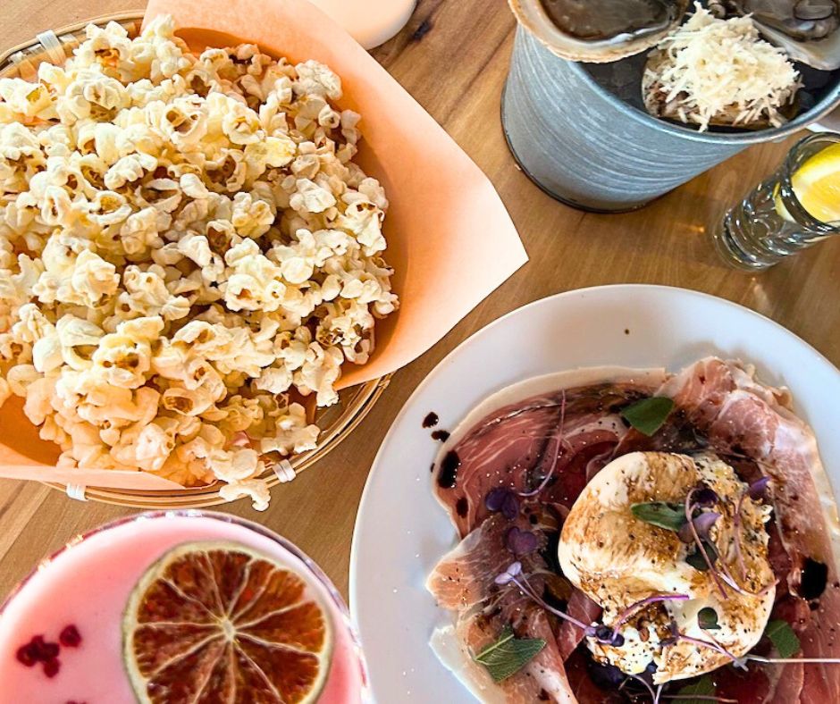 Overhead shot of the food at Penny's include popcorn, cocktail, burrata and oysters
