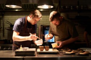 Two chefs plating with tweezers at Perch
