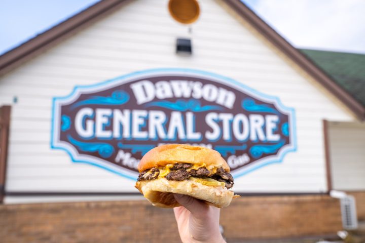 burger held up in front of Dawson General Store sign