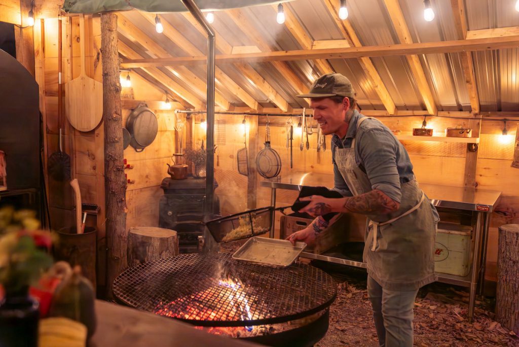 Joel cooking over the fire outside at Down Home