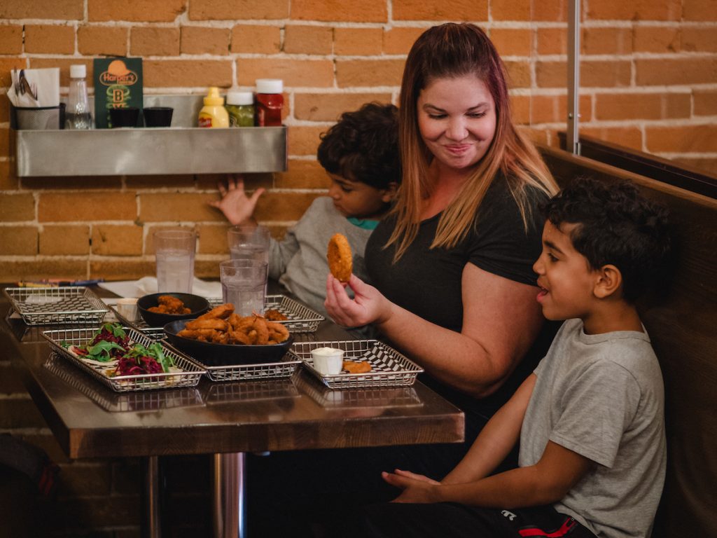 A mom and two sons sitting at the table enjoying onion rings at Harpers Burger Bar