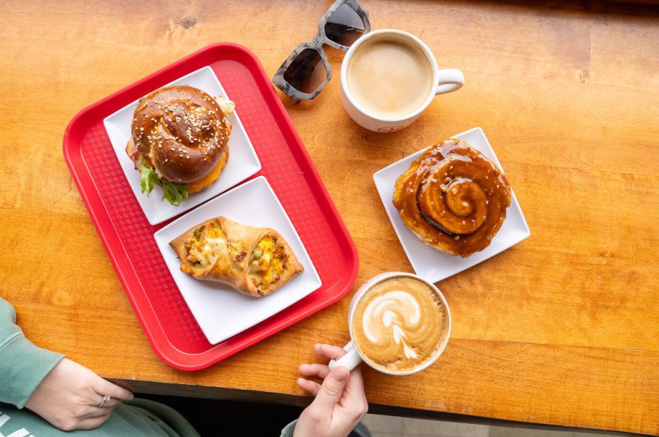 overhead shot of sticky bun, breakfast ray, breakfast sandwich and two coffees at Sweet North Bakery
