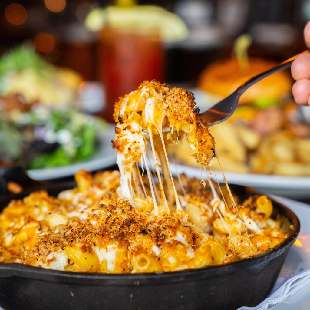 fork in dish with mac and cheese with cheese pull.