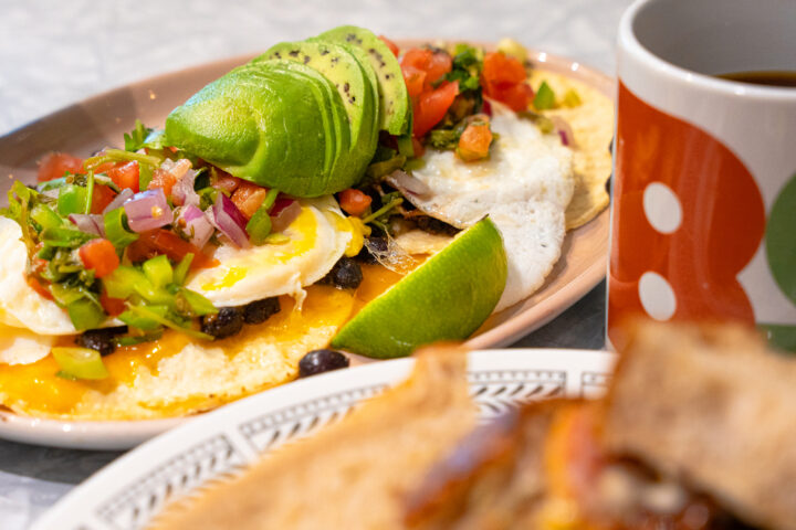 close up of a plate with eggs topped with avocado and tomato salsa.