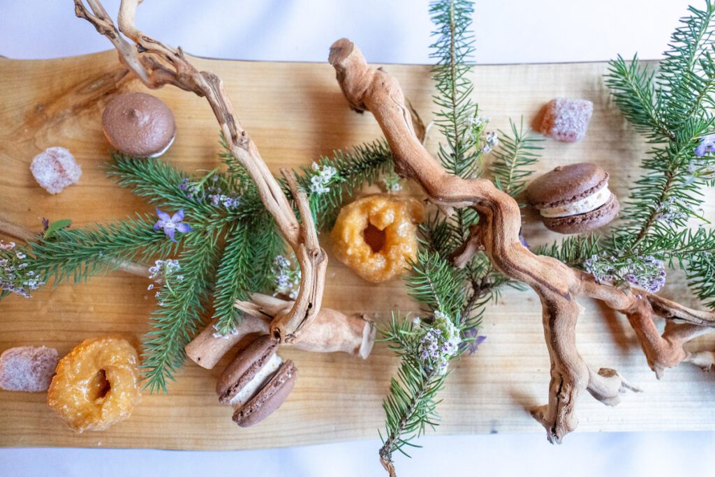 overhead shot of a dessert spread at Haliburton Post House complete with pine branches, homemade donuts and macarons