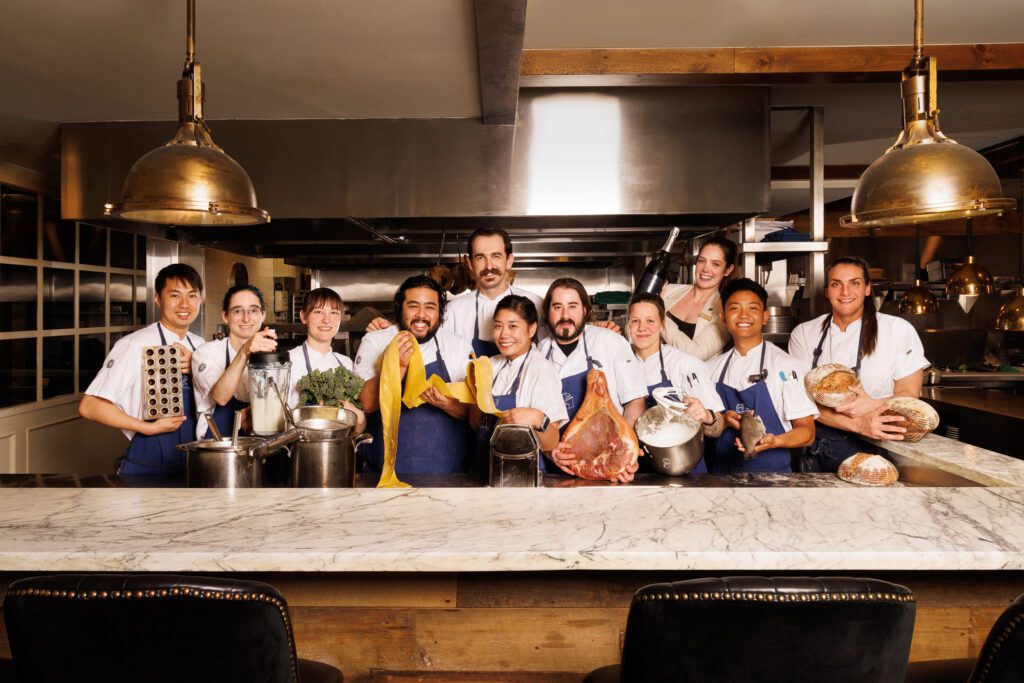 The Elora Mill kitchen staff behind the counter holding various ingredients