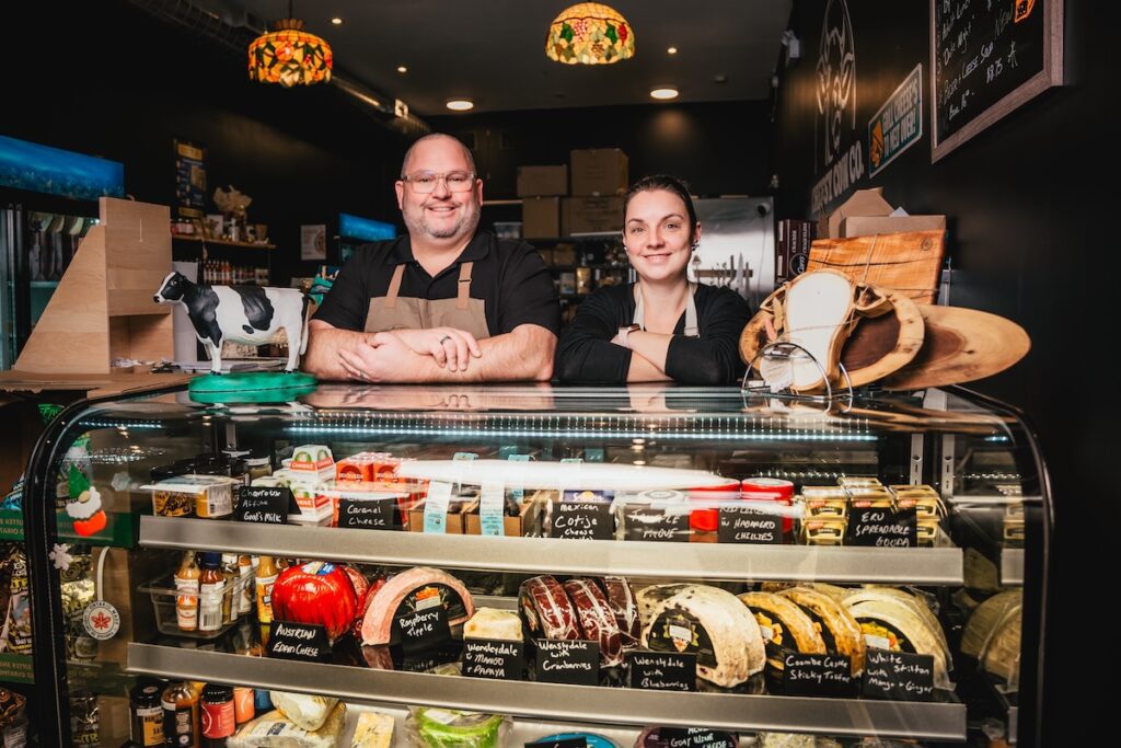 two folks behind the cheese counter at The Cheesy Cow