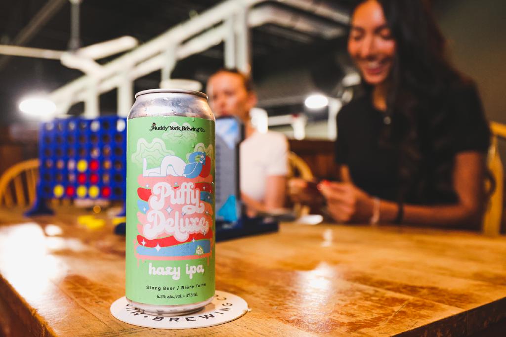 close up of a beer can with people in the background at Muddy York Brewing
