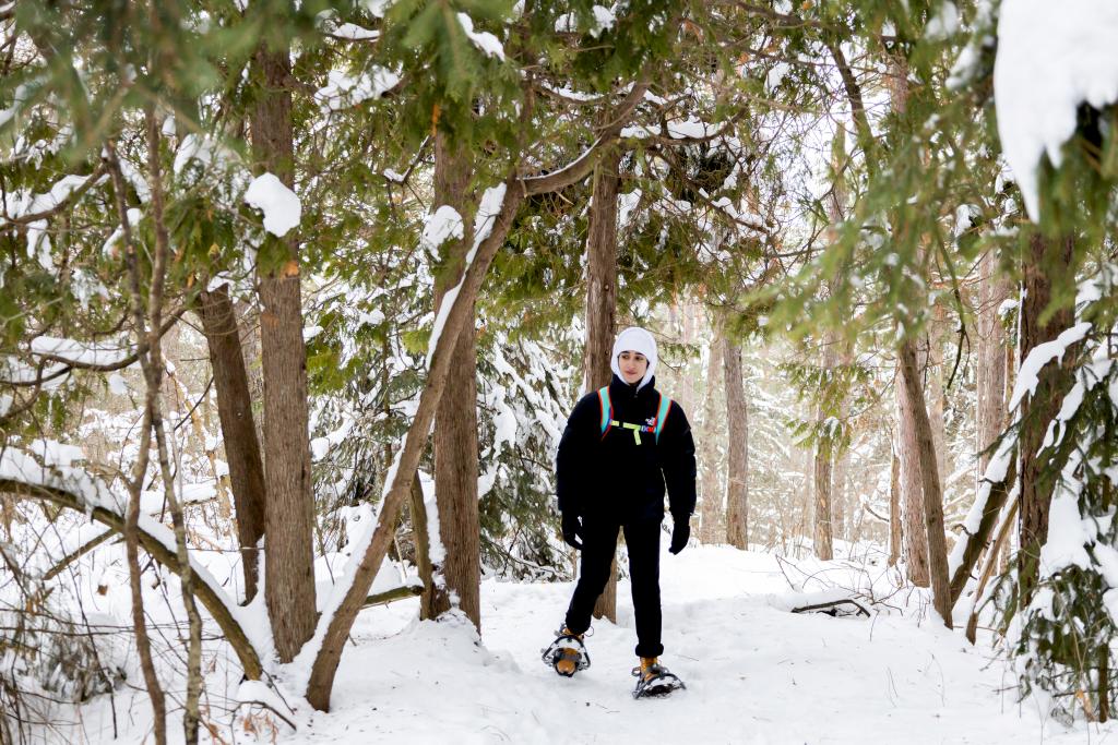 person snowshoeing through the woods at trail hub