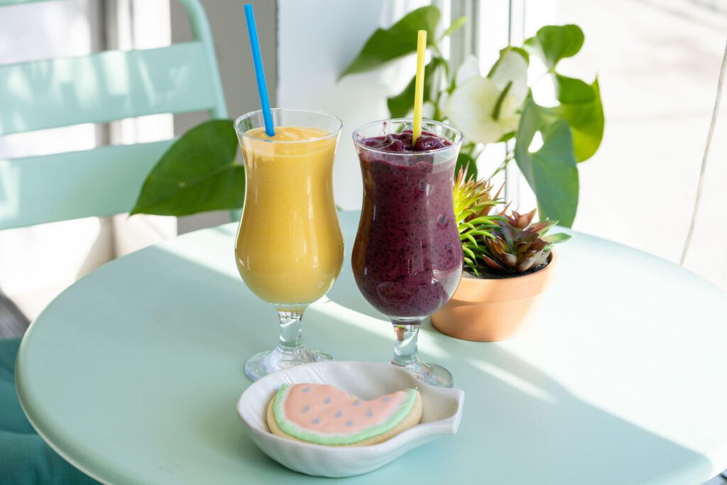 two smoothies and a cookie in the sunshine on a blue table at Tropical Blends Café