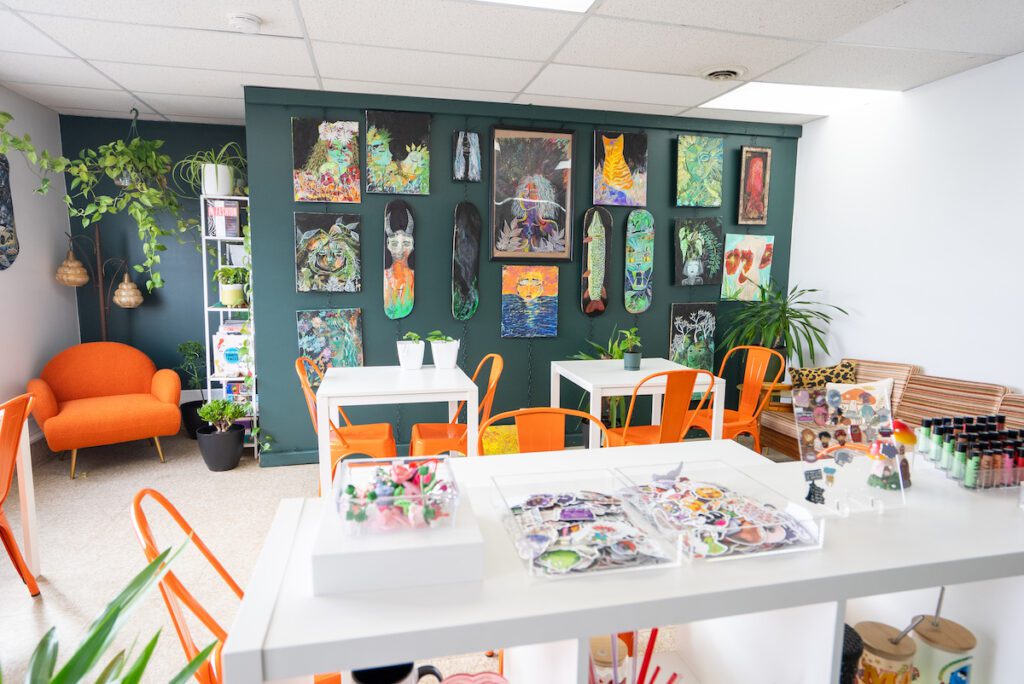 Interior shot of Wavy inside with a green wall, orange chairs and lots of art on the wall including painted skate decks.