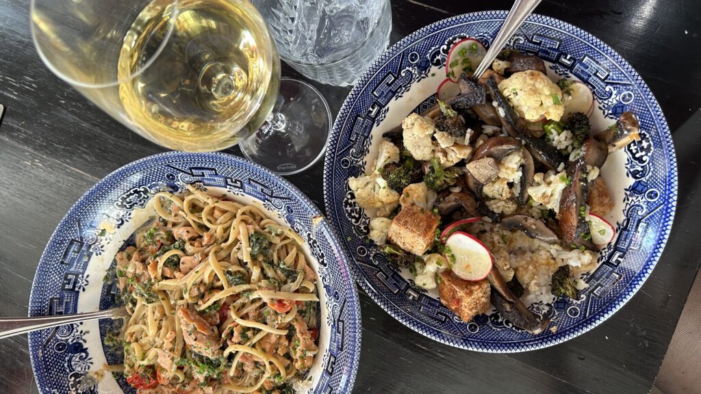 overhead shot of two dishes and a glass of wine at the evelyn