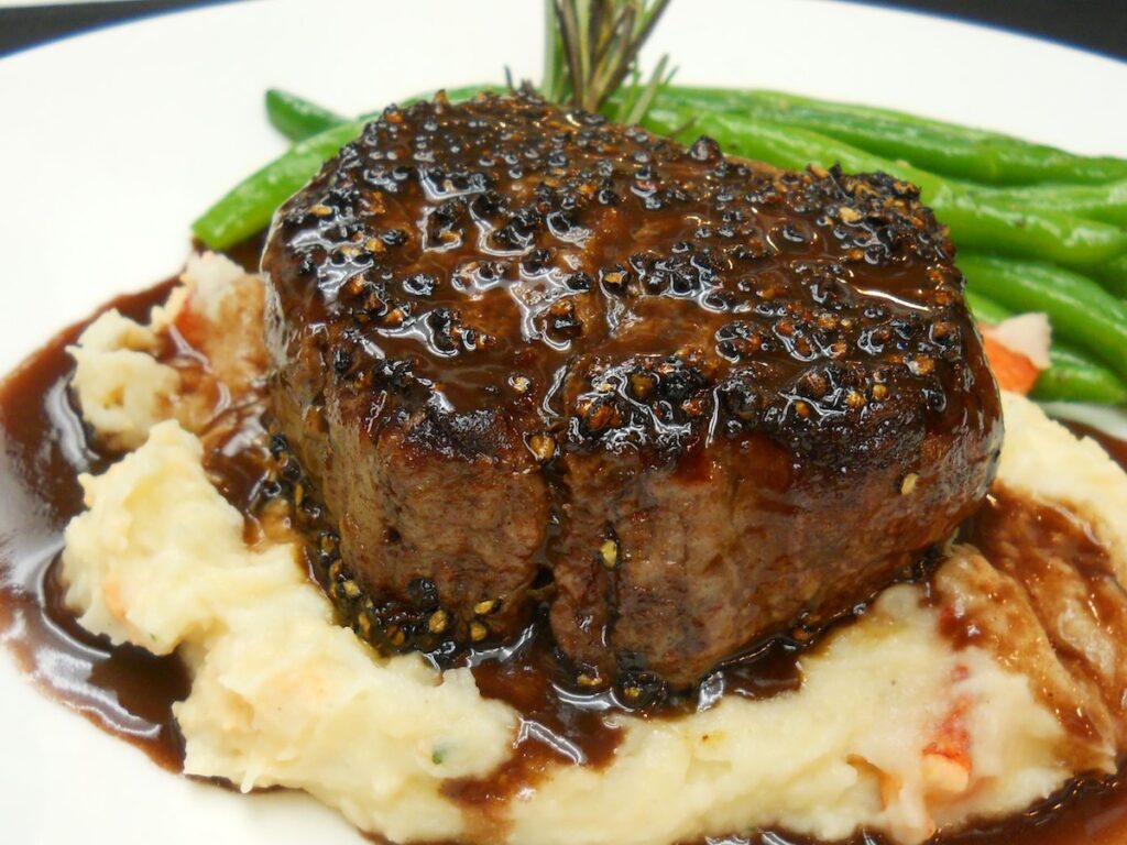 peppercorn steak with green beans on mashed potatoes at 1886