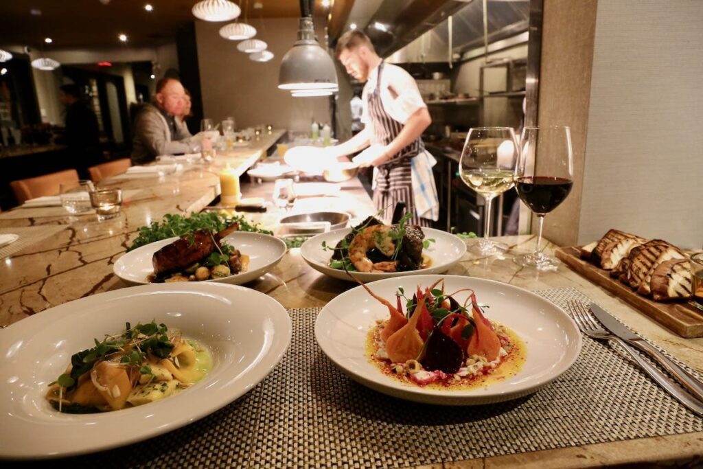 Chef counter at Treadwell restaurant lined up with plates, a chef at the end talking nto a patron