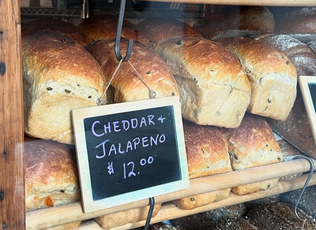 cheddar and jalepeno bread in the window with a chalk board sign