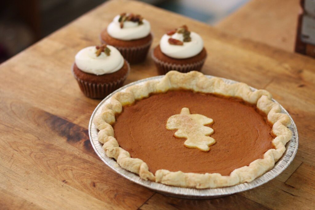 pumpkin pie and cupcakes on a wood counter