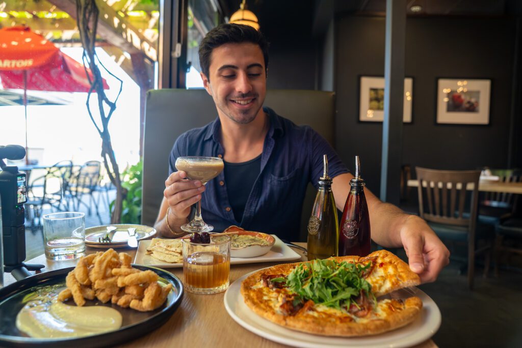 Man with pizza, calamari and cocktails at Kouzzina