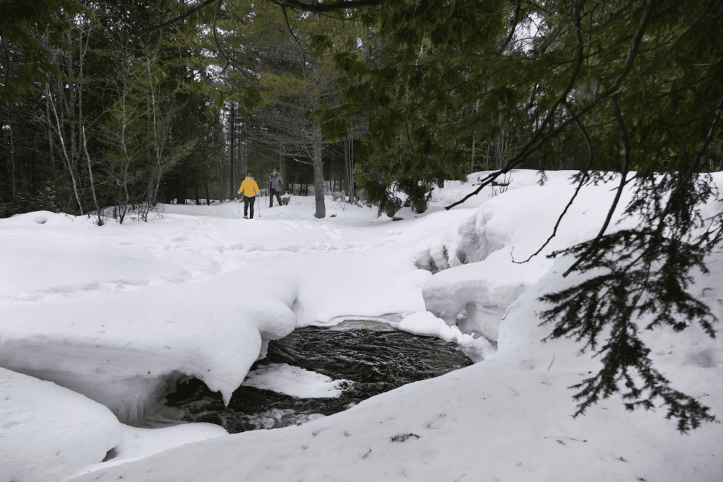 two people snowshoeing around the river at Duchesnay Falls