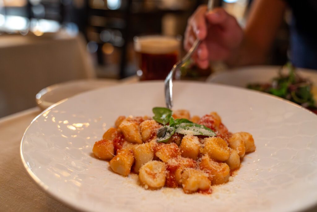 Hand holding a fork twirling shell-shaped pasta at Verdicchio Ristorante in Sudbury.