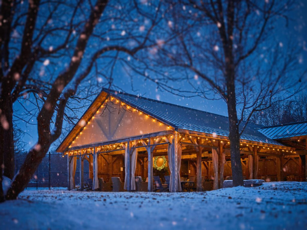 exterior shot of the event space at Langdon Hall lit up for the holidays with snow on the ground and coming down lightly from the sky