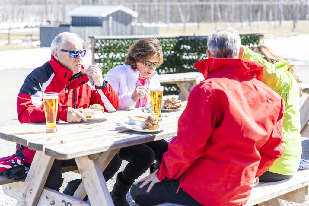 two couples eating burgers and drinking beer at quayle's in their winter coats outside