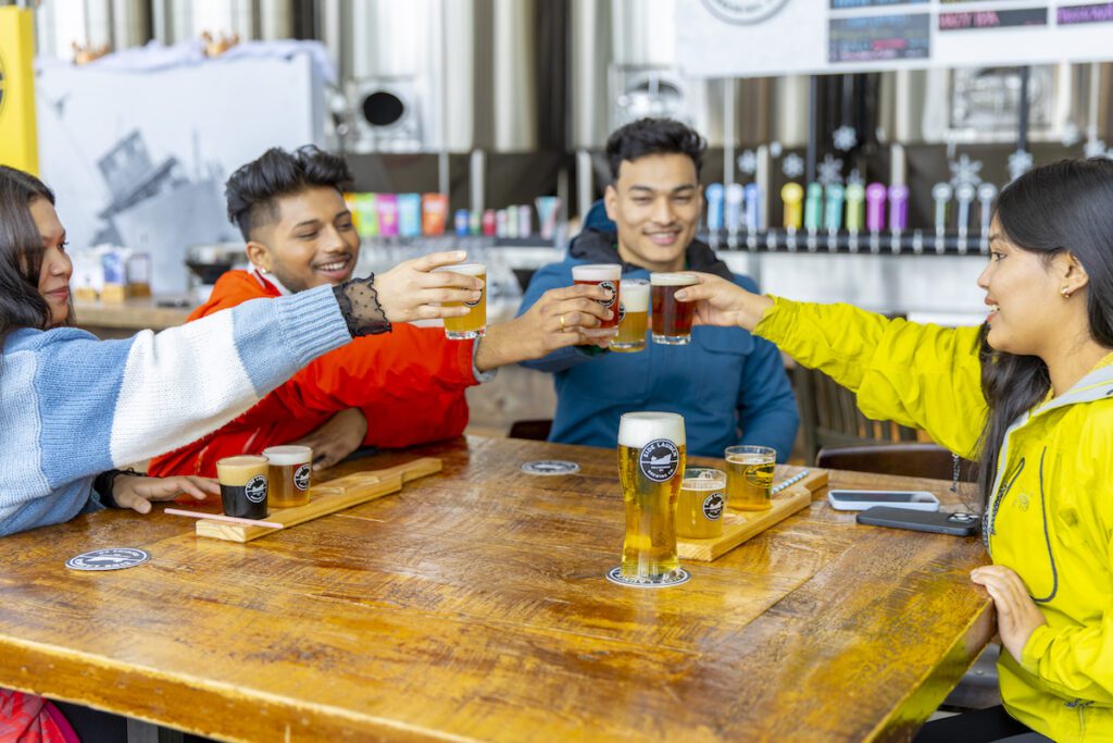 Two couples cheersing beers at Side Launch Brewing Company