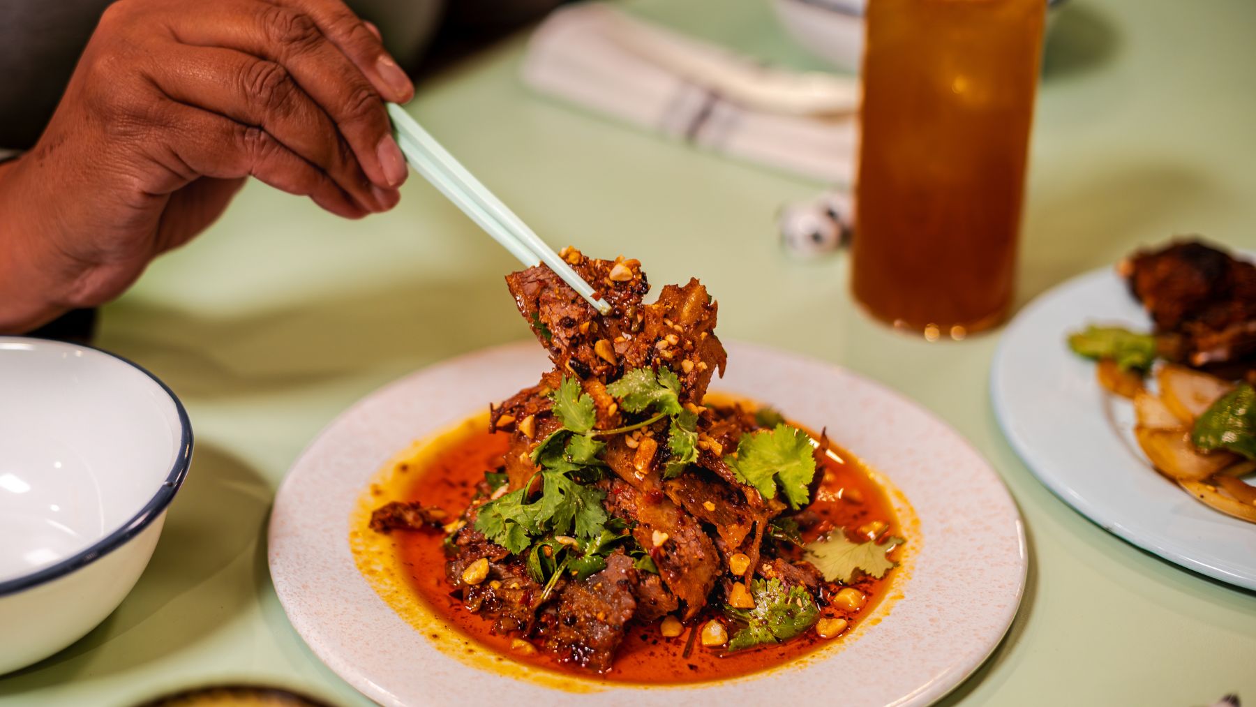 hand picking up brightly coloured dish with chop sticks at Sunny's Chinese