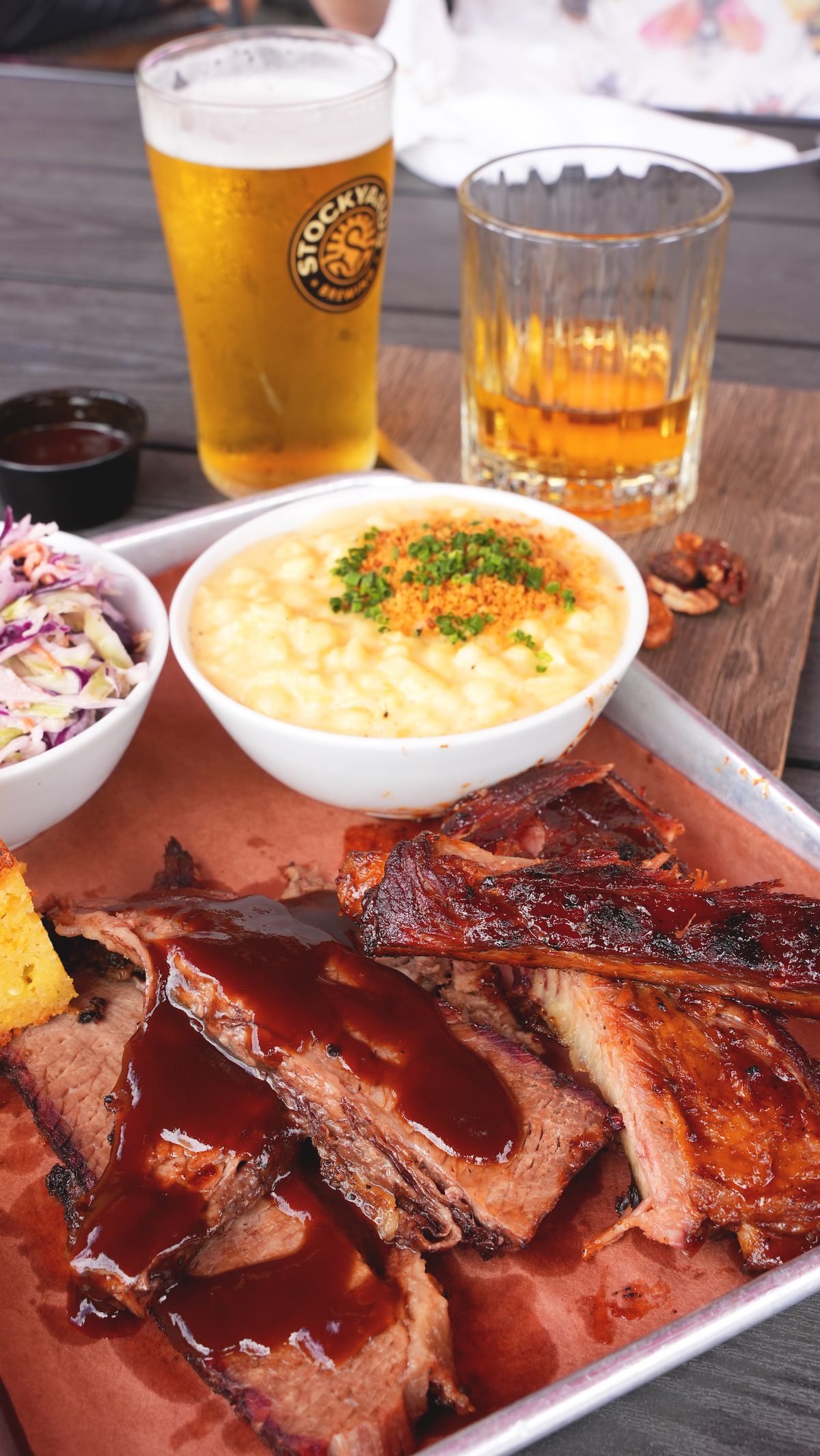 photo of crowsfoot meal including brisket, macaroni, coleslaw, a beer and a cocktail