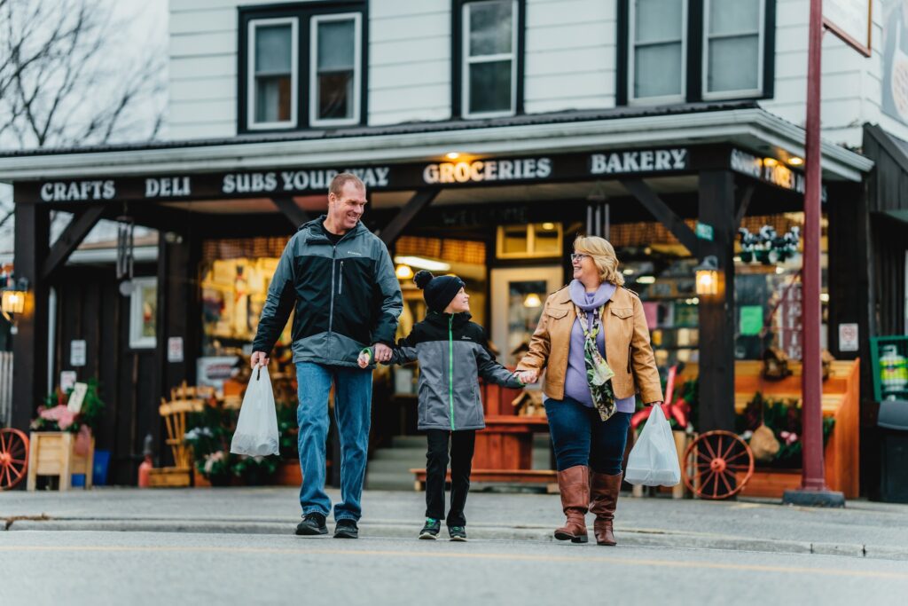 two adults and one child walking hand in hand out of the Kent Bridge Country Market with bags in hand