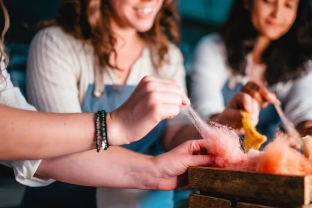 three women in aprons pulling felt apart
