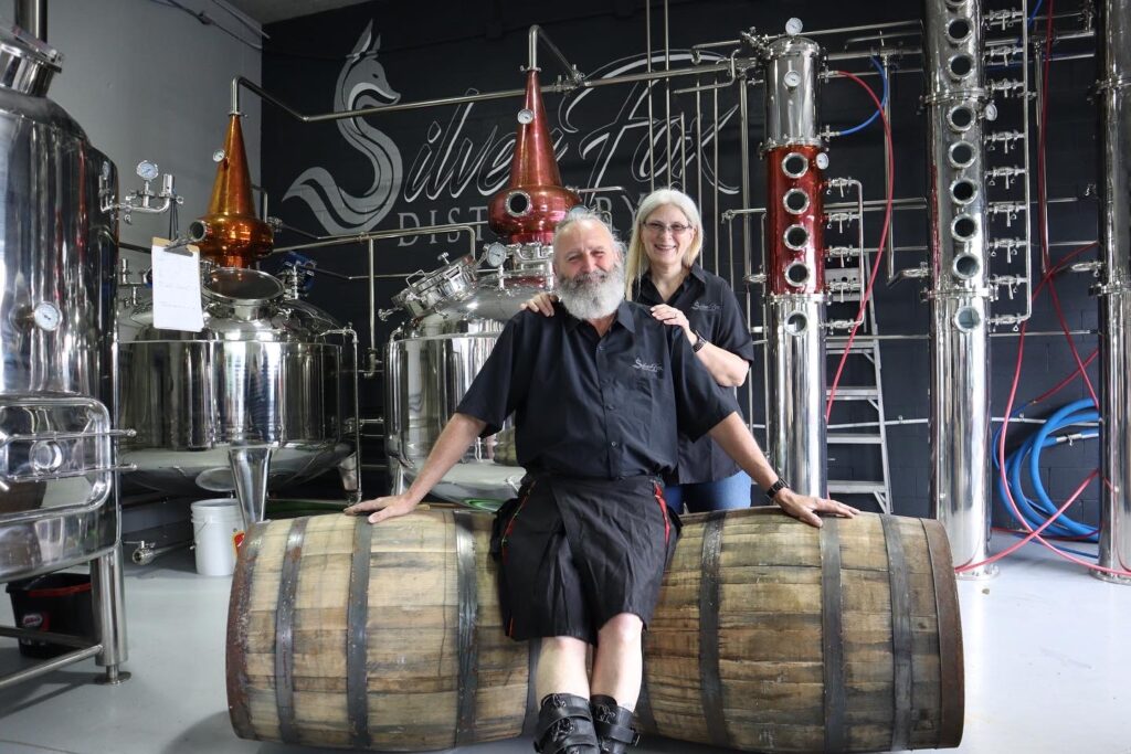 Owners of Silver Fox Distillery sitting on a barrel